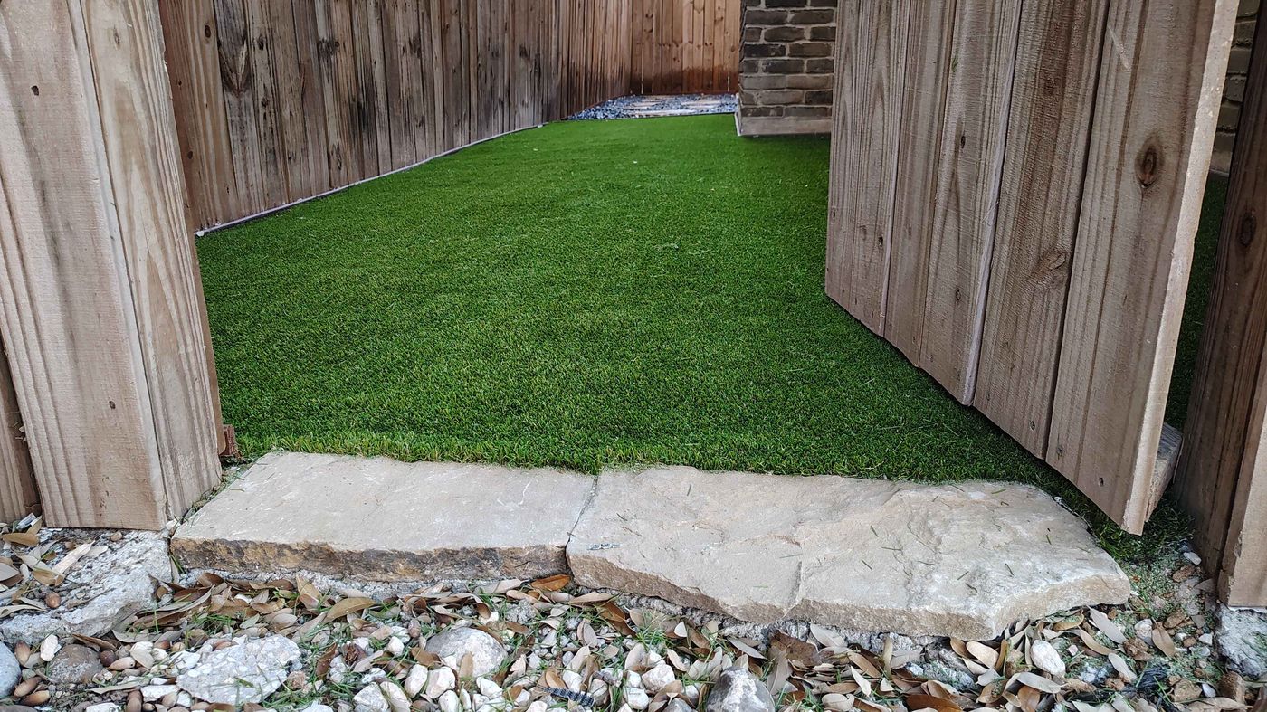 Artificial turf patio with flagstone step and river-rock border
